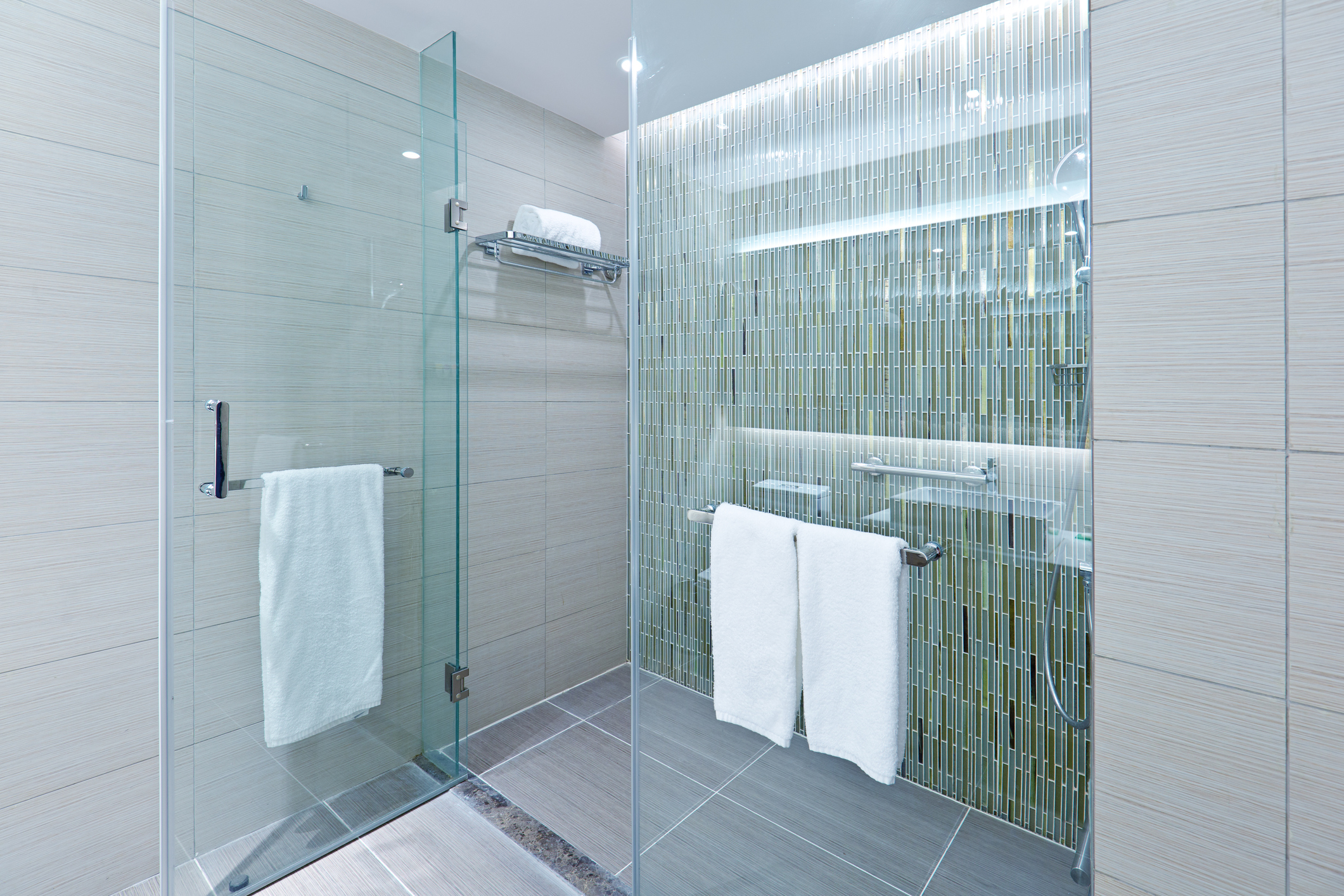 A contemporary modern bathroom design. Glass enclosed shower stall with porcelain tiles. A newly remodeled bathroom.